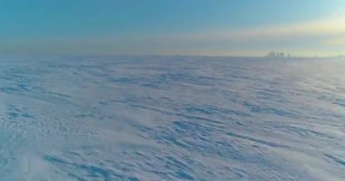 Soğuk kış kutup bölgesinin insansız hava görüntüsü, ufukta karla kaplı ağaçlar, buz nehri ve güneş ışınları. Aşırı düşük sıcaklık havası.
