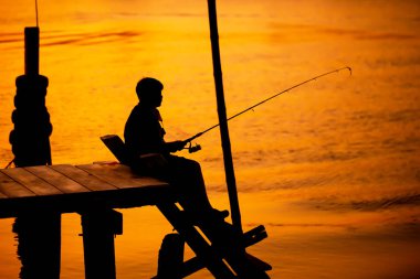 Nehir kıyısında oturan bir adamın gölgesi