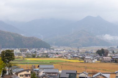 Japonya 'nın Kyoto kentindeki dağlarla çevrili yerel evler ve pirinç tarlalarının doğal manzarası.