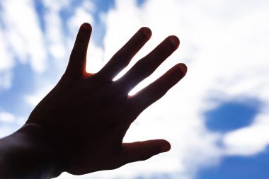 Mavi arka planda siyah elbiseli genç bir adamın eli.