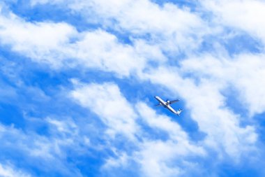 Beyaz bulutla mavi gökyüzünde uçan bir uçak