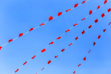 Mavi gökyüzünde kırmızı ve mavi bayraklar.