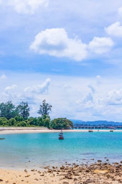 Mavi gökyüzü ve beyaz denizi olan güzel bir kumsal görüntüsü.