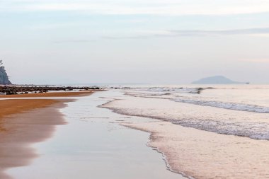 Akşamları dalgalar ve kayalarla denizin üzerinde gün batımı