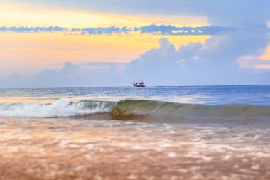 Gün batımında kumlu bir sahilde sörf tahtası olan güzel bir tekne manzarası.