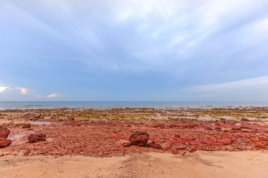 Taşlı deniz kumsalı ve bulutlu mavi gökyüzü
