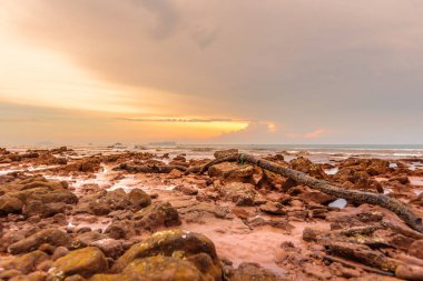 Günbatımında kayalar ve deniz olan güzel tropikal plajlar