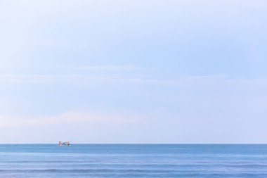 Beyaz bulutlu mavi deniz ve arka planda güneş..