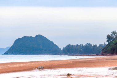 Uzakta kayalar ve dalgalar olan Pasifik sahilinin kumlu bir sahili.