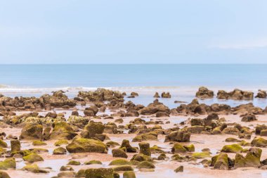 Dalgalı güzel deniz manzarası, kayalar ve beyaz bulutlu mavi gökyüzü.
