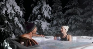 Bir çift kışın kaplıcada jakuzide dinleniyor.