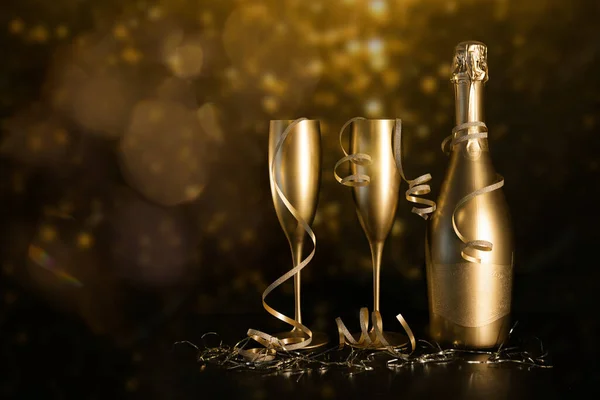 金色のシャンパンボトルとブラックボケの背景にリボン付きのグラス2つ お正月とお祝い コピースペース — ストック写真