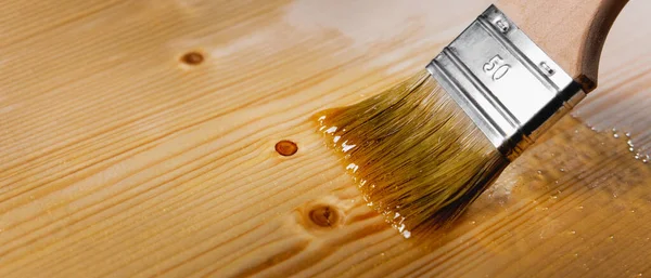 木に透明ワニスを塗料ブラシで塗ります 木製家具のコーティングと保護 コピースペースのバナー — ストック写真