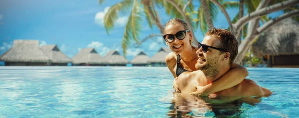 热带度假胜地暑假 这对快乐的夫妇在游泳池里放松一下 背景是水上平房 带有复制空间的横幅 — 图库照片