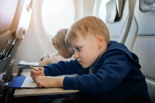 kids fly in airplane and draws with pencil in coloring book. travel with children