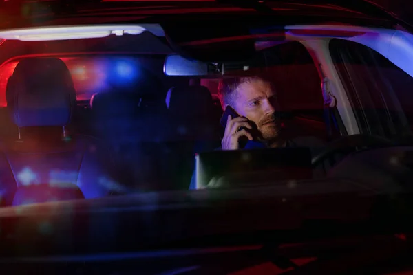 stock image man sitting inside a car and talking on the phone after being stopped by police at night