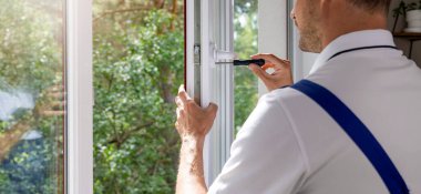 Plastik PVC pencere kolu takan bir işçi. Bakım ve onarım. Kopyalama alanı olan pankart