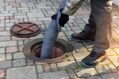 Boru tutan ve evdeki foseptiği pompalayan işçiler. drenaj ve kanalizasyon temizleme servisi