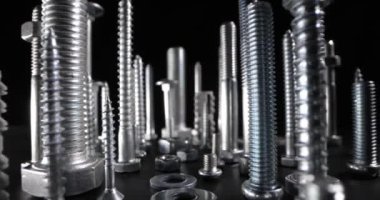 Siyah arkaplanda metal vidalar, cıvatalar ve bağlayıcılar