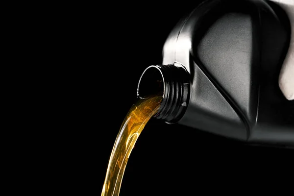 pouring new motor oil from bottle into car engine. isolated on black background