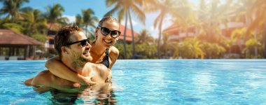 Gülümseyen mutlu çift yüzme havuzunda birlikte eğleniyor. Yaz tatili, kaçış seyahati. Kopyalama alanı olan pankart