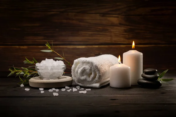 wellness spa. body skin care items on dark wooden table. towel, bath crystals, massage stones and candle