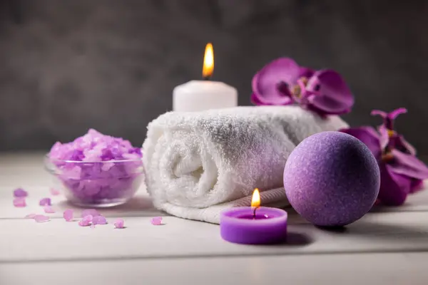 紫色浴弹 海盐水晶 毛巾和香味蜡烛放在木制桌子上 身体皮肤护理 健康温泉A 图库图片