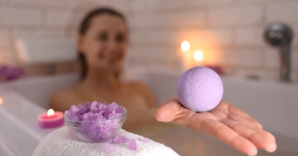 女人躺在浴缸里 在烛光下放松 手里拿着浴弹 让身体皮肤保湿 家庭温泉 — 图库视频影像
