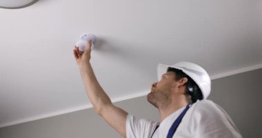 Yangın güvenlik mühendisi evin tavanına fotoelektrik duman dedektörü yerleştiriyor. ev güvenliği ve yangın alarmı sistemi