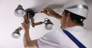 Tamirci servisi. Elektrikçi eve tavan lambası yerleştiriyor