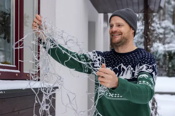 家の外装の装飾のためのクリスマスのセーターの屋外で幸せな男 ロイヤリティフリーのストック写真