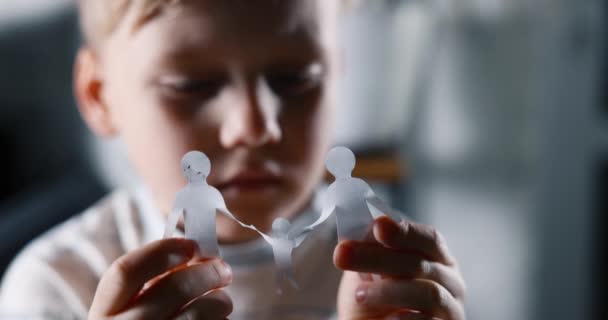 一个悲伤的小男孩 手里拿着纸制的家庭 家庭问题 监护和虐待儿童的概念 — 图库视频影像