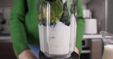 Kadın evde sebze, meyve ve yoğurttan sağlıklı smoothie yapıyor. Blender yakın plan