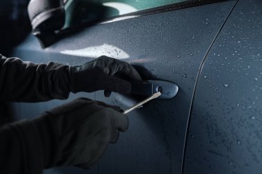 Tornavidalı bir araba hırsızı kapı kilidini kırıp gece araba çalıyor.