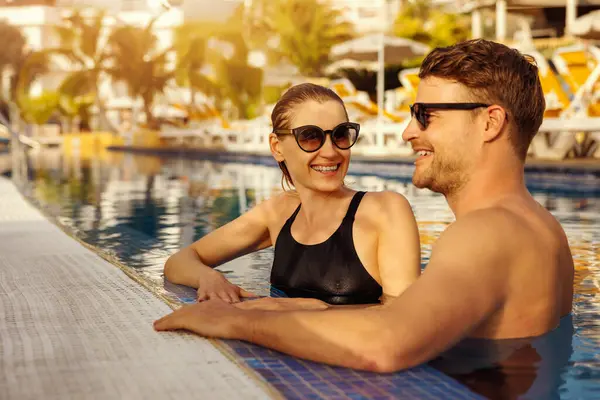 Genç mutlu çift tropik tatil köyü havuzunda birlikte dinleniyor. Yaz tatili, romantik bir tatil.