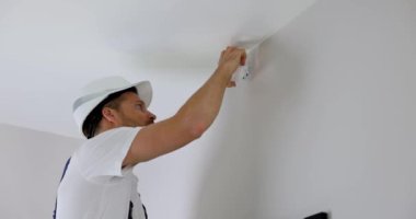Güvenlik sistemi teknisyeni evdeki duvara hareket sensörü yerleştiriyor.