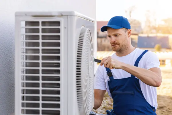 在室外空调或热泵上工作的技术人员 暖通空调服务 维修和保养 图库照片