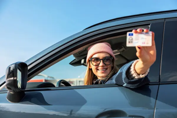 Uśmiechnięta Kobieta Pokazuje Swoje Nowe Prawo Jazdy Przez Okno Samochodu Zdjęcie Stockowe