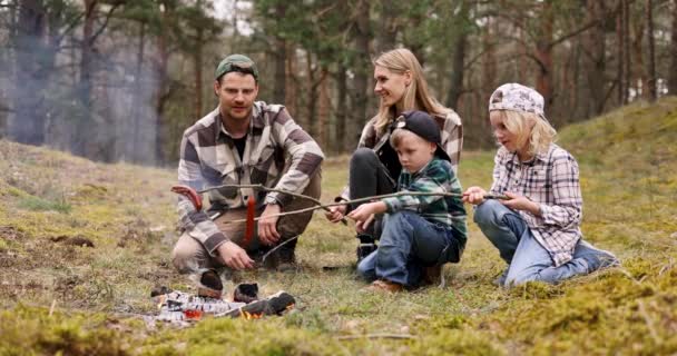 森でキャンプしている間 木の歪みでソーセージをかぶっている子供たちと家族 自然の冒険 ボンディング活動 — ストック動画