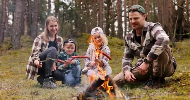 子供がいる家族は森のキャンプファイヤーの上に木の歪みでソーセージを調理します 自然ピクニック アウトドア活動 — ストック動画