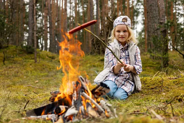 小女孩在森林篝火上煎香肠 户外活动 图库图片