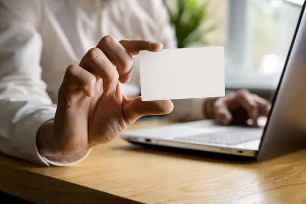 Homem Mostrando Cartão Visita Branco Enquanto Trabalhava Laptop Escritório Mockup Fotografias De Stock Royalty-Free