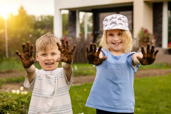 Enfants Gais Montrant Sales Mains Boueuses Extérieur Dans Jardin Image En Vente