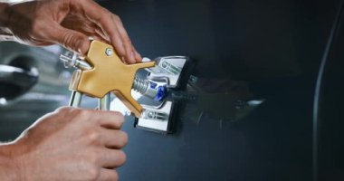 Acısız araba çukur onarım aleti. Adam PDR teknolojisiyle araç kapısını tamir ediyor.