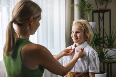 Annesi giyinmesine ve kızına evde ilk okul günü için destek olmasına yardım ediyor.