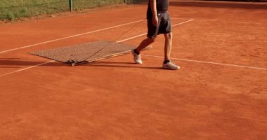 Adam temiz kil tenis kortu. Yüzeyi düzleştiriyor