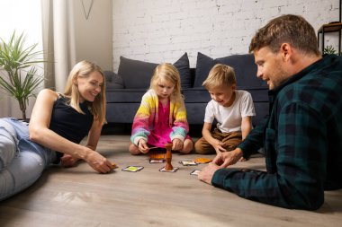 Mutlu ve çocuklu bir aile evde eğleniyor, yerde masa oyunları oynuyorlar. bağlanma etkinlikleri