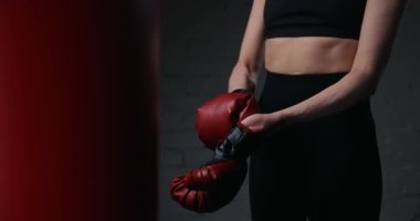 Spor salonunda antrenman yapmadan önce boks eldiveni giyen bir kadın.