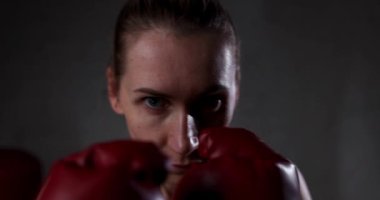 Spor salonunda boks eldivenli ciddi odaklı bir kadın. Güç, kararlılık ve konsantrasyon kavramı