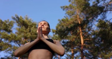 Gün doğumunda ormanda pilates ya da yoga yapan bir kadın. Zihin-beden egzersizleri, zihinsel refah ve meditasyon.